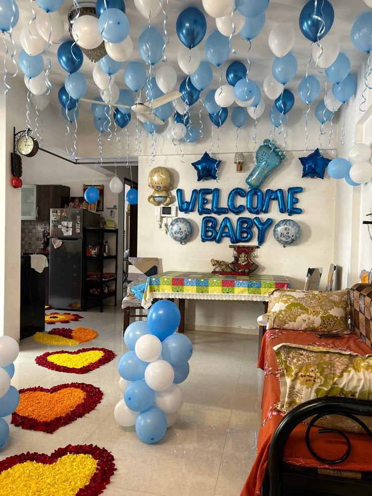 Blue and white balloons with a welcome baby backdrop and flower rangoli